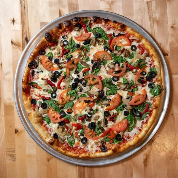 A whole NY Pizza Place veggie pizza with tomatoes, spinach, mushrooms, olives, and peppers.